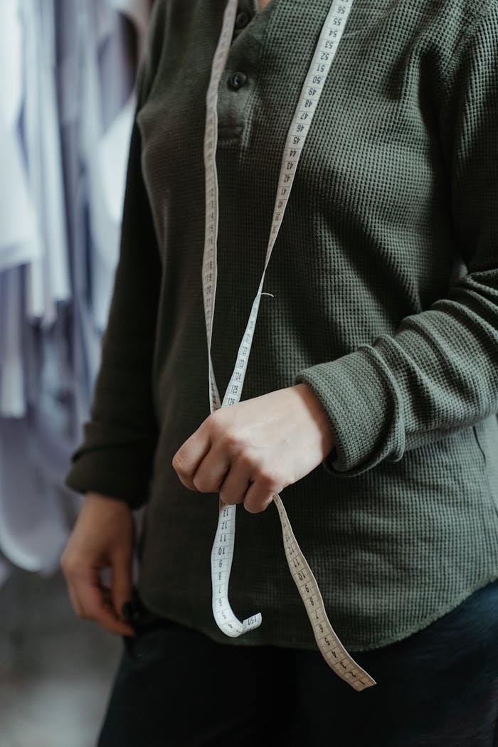 Female tailor with measuring tape in a fashion studio, emphasizing the professions precision.
