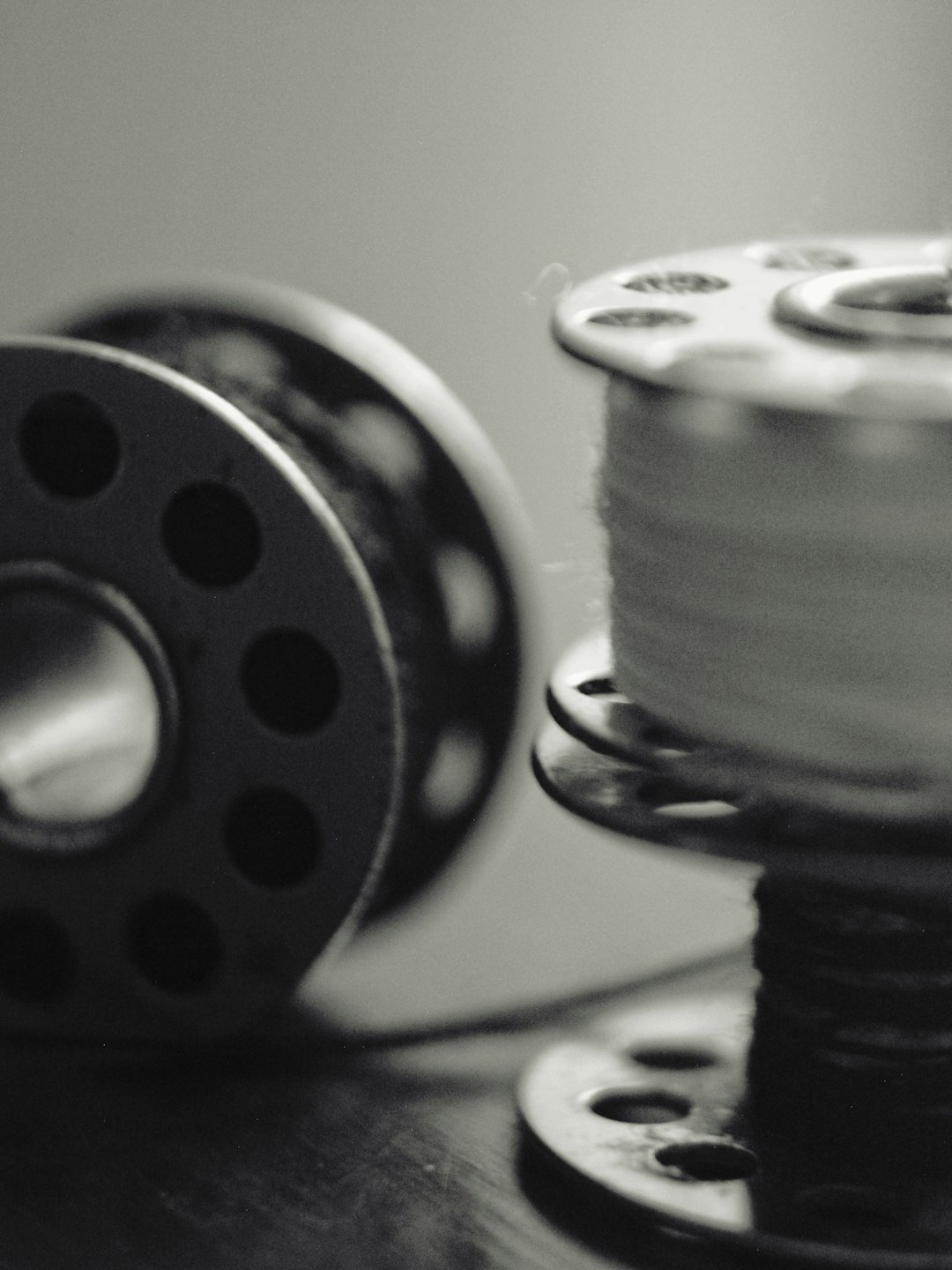 two-sewing-bobbins-one-with-thread-in-black-and-white-ise2njjafjc