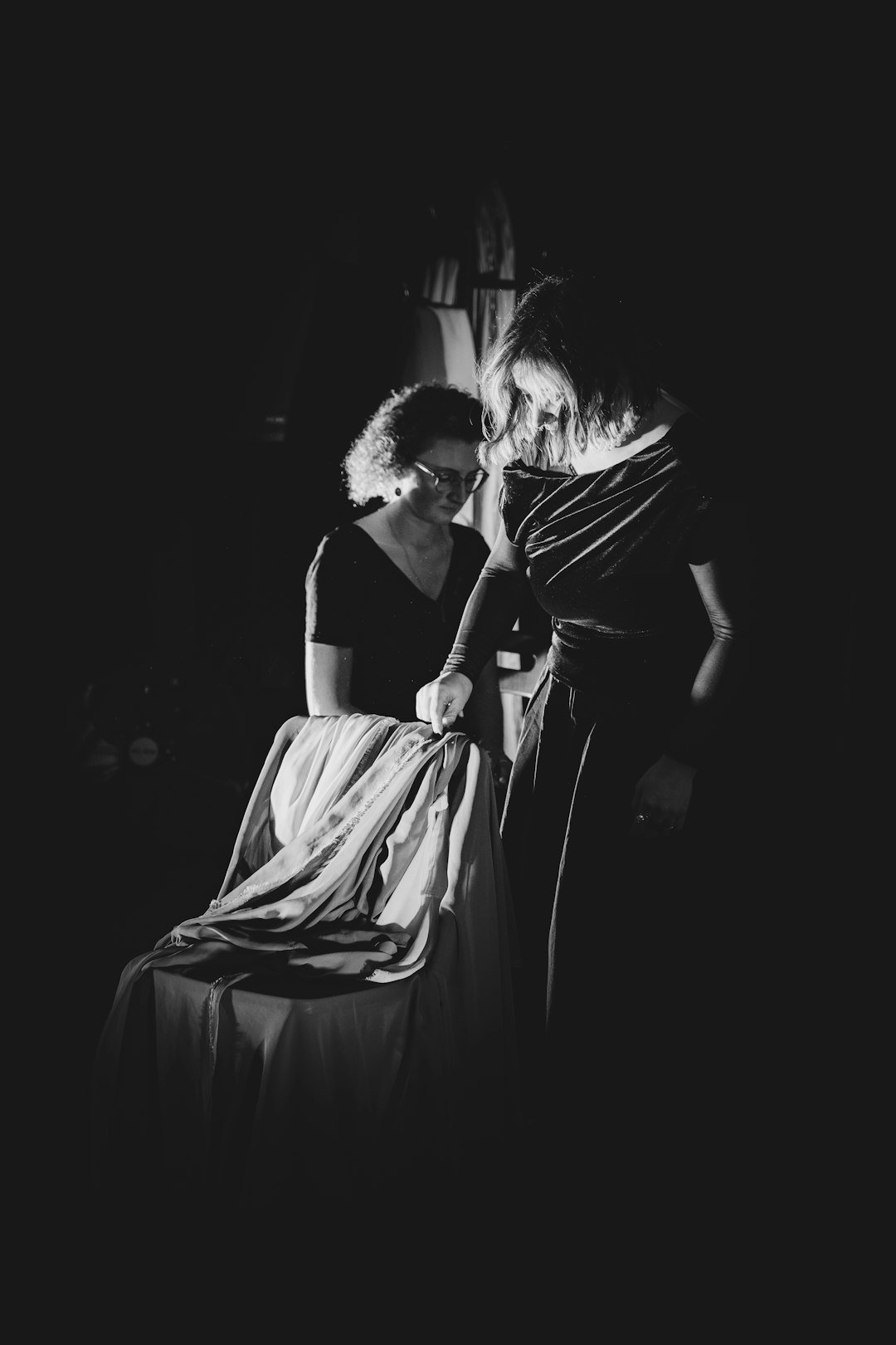 two-women-examining-fabric-in-dim-lighting-vwylp3um2sa